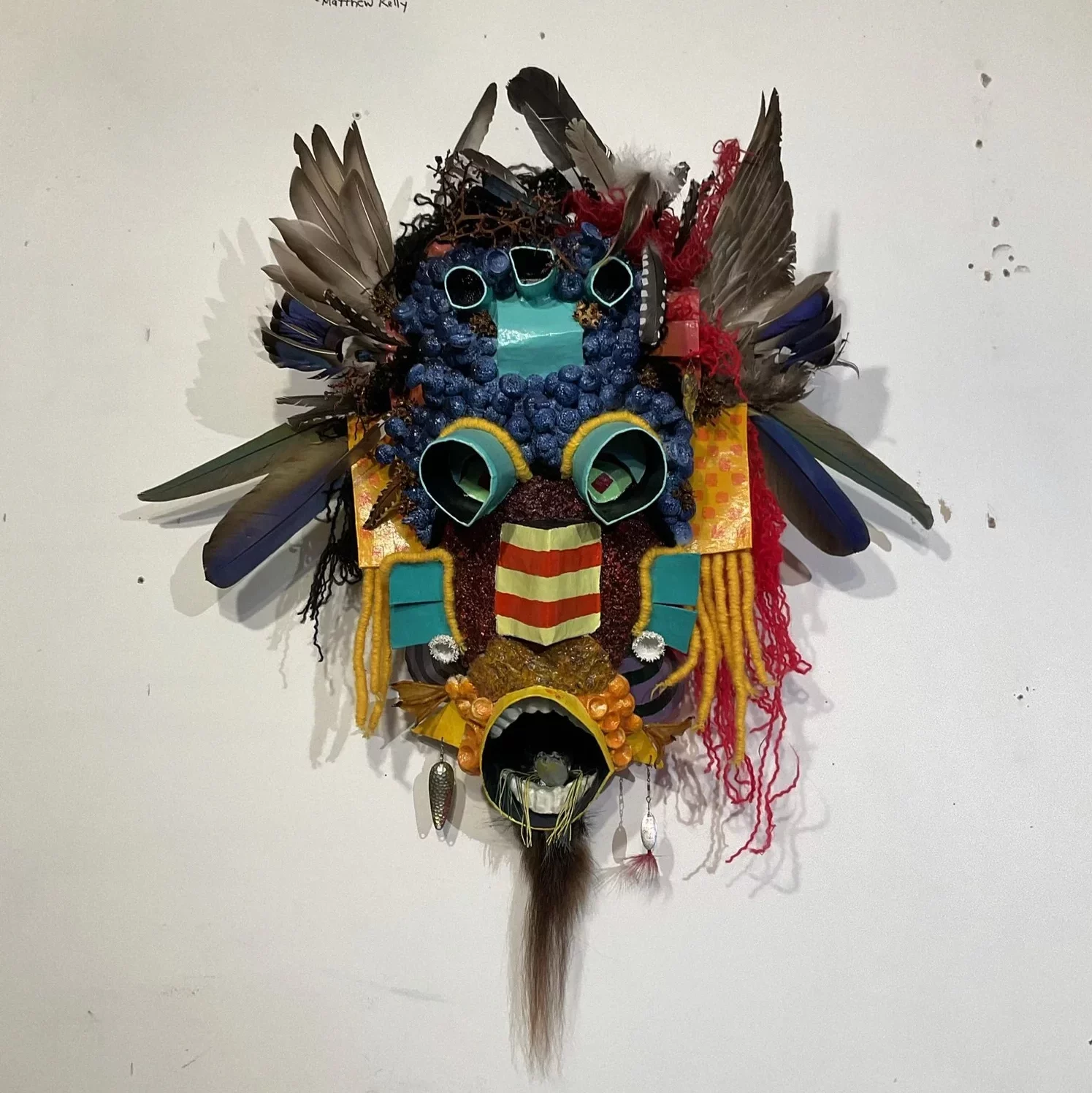 A colorful mask adorned with feathers and decorative materials.
